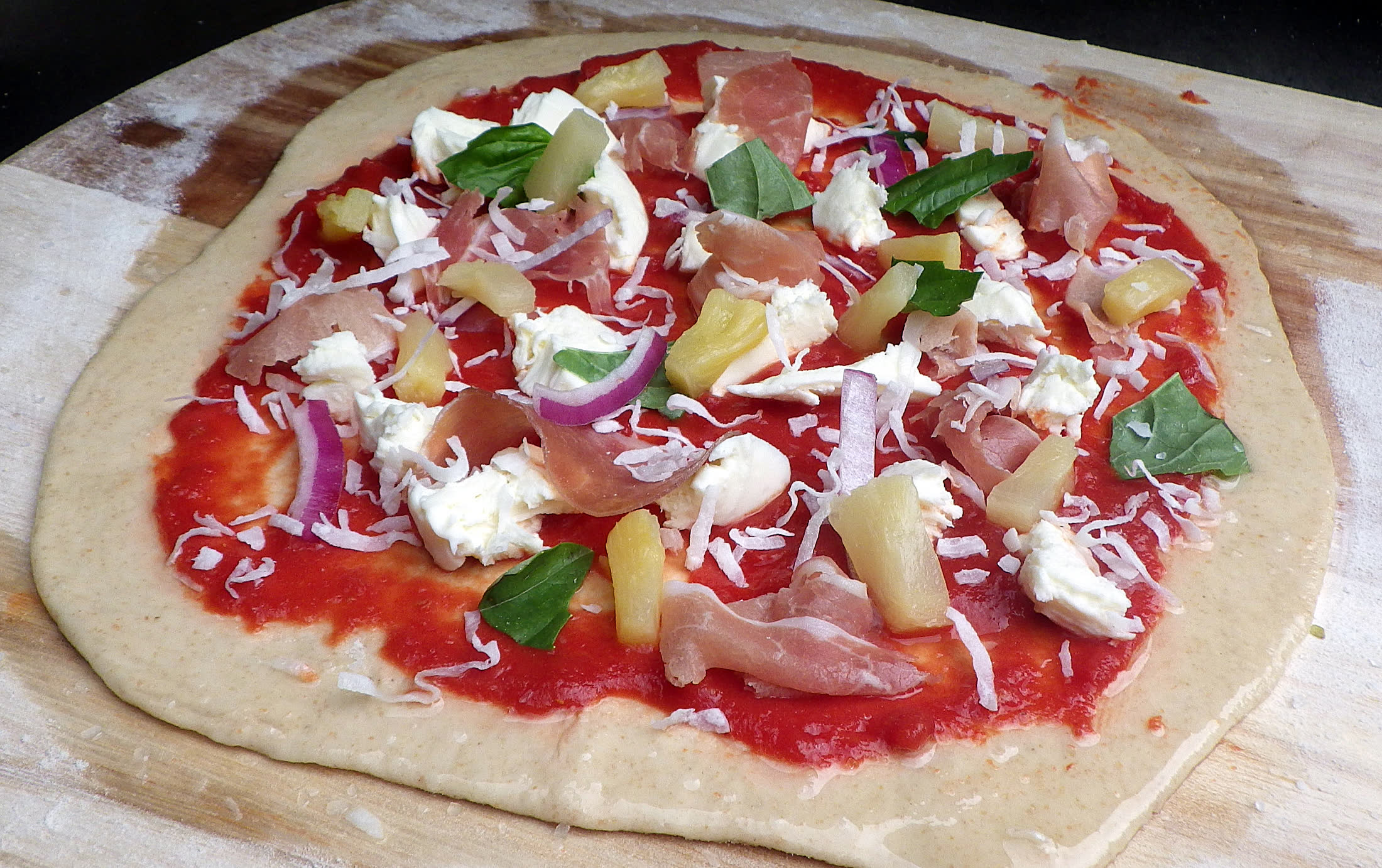 A Margherita-style pizza topped with mozzarella, basil, and prosciutto