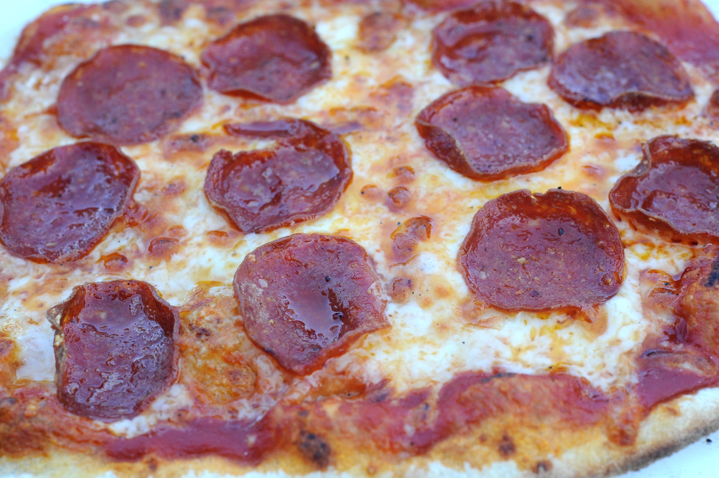 A thin-crust pepperoni pizza fresh from the wood-fired oven
