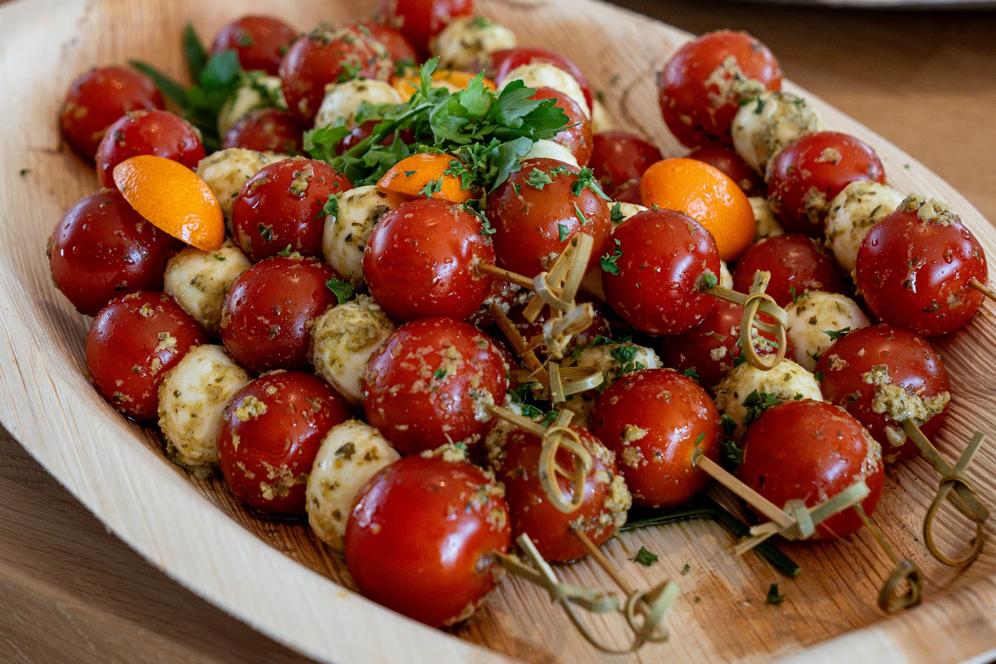A platter of cherry tomato, mozzarella, and herb skewers